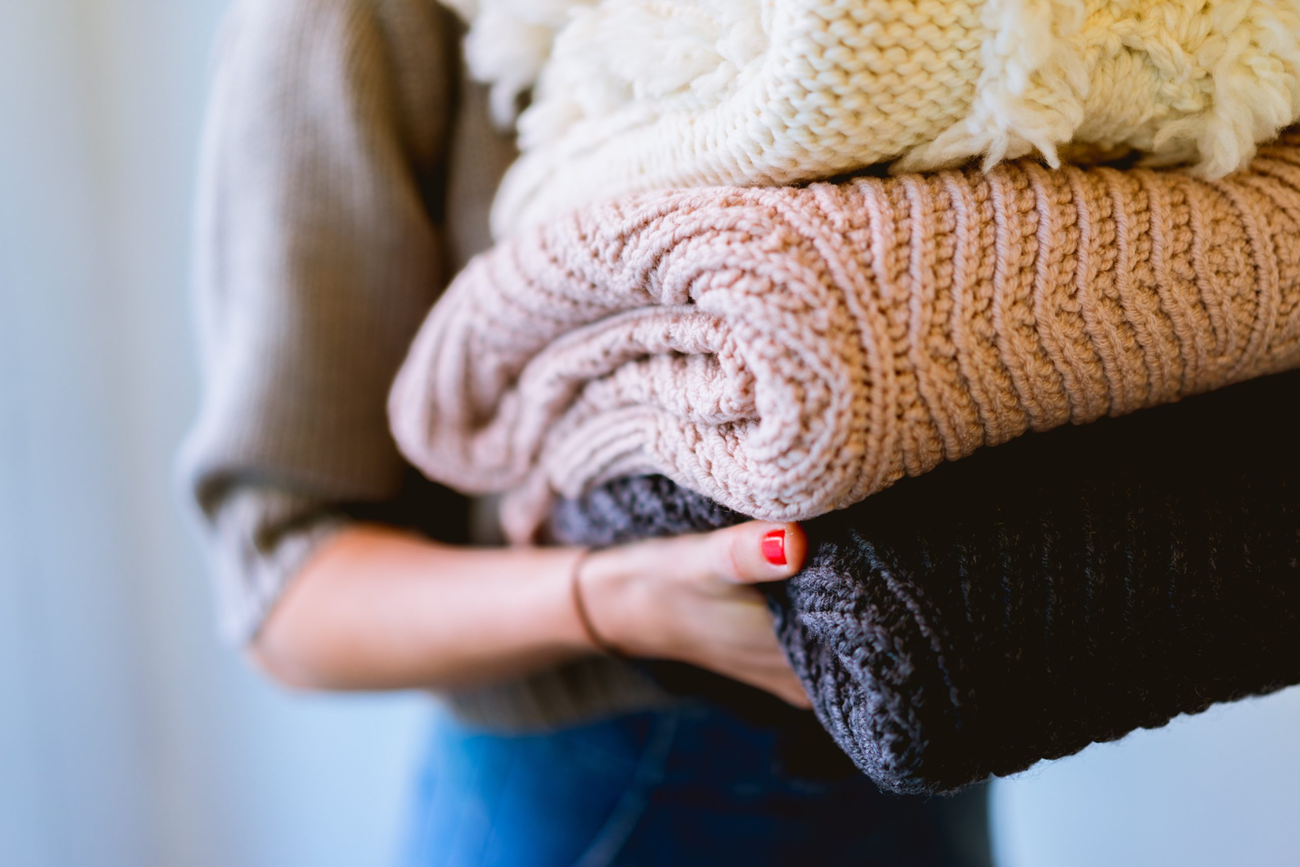 kobieta trzymająca świeżo wyprane swetry